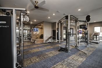 A gym with weights and cardio equipment and a ceiling fan